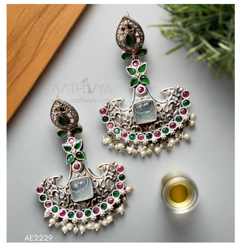 Ornate earrings with gemstones on a light surface