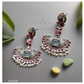 Ornate silver earrings with gemstones on a gray background