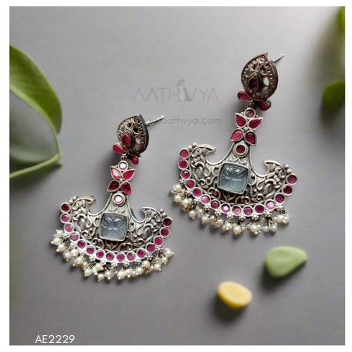 Ornate silver earrings with gemstones on a gray background