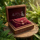 Jewelry set in a wooden box with 'Aathra' branding, surrounded by green foliage.