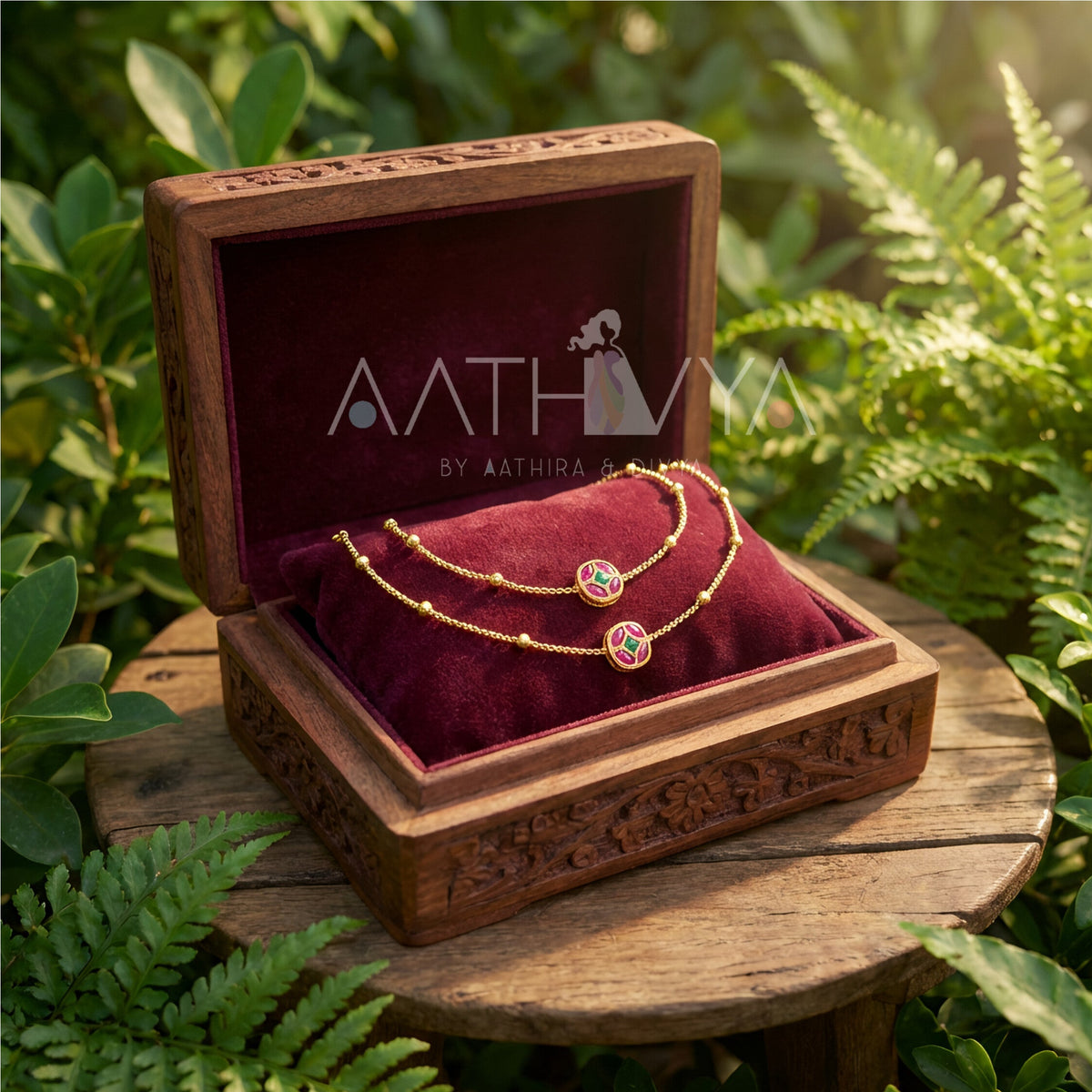 Jewelry set in a wooden box with 'Aathra' branding, surrounded by green foliage.