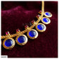 Gold chain necklace with five oval blue stones and small pink accent stones, displayed on a dark burgundy velvet background.