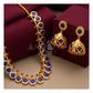 Gold jewelry set featuring a necklace and matching earrings with deep blue oval stones and small red accent stones, displayed on dark burgundy boxes against a beige background.