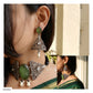 A woman wearing ornate silver-toned jewelry, including a choker necklace and matching drop earrings with green stone and pearl details, shown in a close-up collage view.